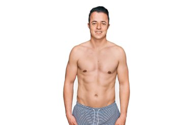 Yüzünde mutlu ve havalı bir gülümseme olan mayo giyen yakışıklı bir genç. şanslı kişi. 