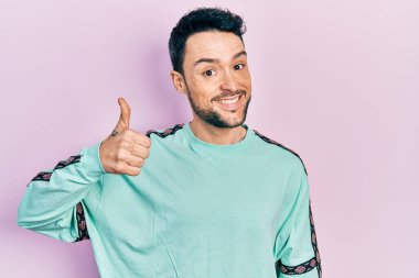 Neşeli ve pozitif gülümseyen İspanyol asıllı genç adam, mükemmel ve onay işareti yapıyor. 