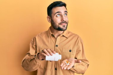 Genç İspanyol adam elinde haplarla gülümsüyor, yan tarafa bakıyor ve düşünüyor.. 