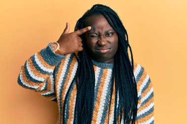 Örgülü, sıradan bir kazak giyen genç siyahi kadın alnındaki sivilceden mutsuz, siyah noktalı çirkin bir enfeksiyon taşıyor. sivilce ve deri problemi 