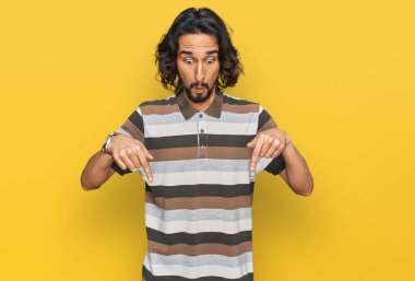 Gündelik giysiler giymiş genç İspanyol bir adam parmaklarını göstererek reklamını yapıyor, şaşırmış bir yüz ve ağzını açıyor. 