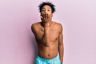 Sakallı, mayo giymiş genç Afro-Amerikan bir adam kameraya bakıp havada bir öpücük savuruyor ve çok güzel ve seksi. aşk ifadesi. 