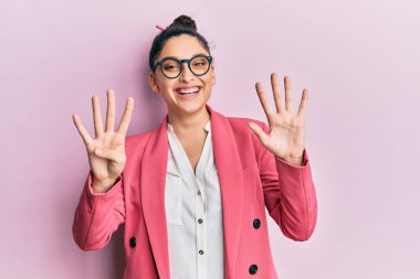 Orta Doğulu güzel bir kadın iş ceketi ve gözlük takıyor dokuz numaralı parmaklarıyla işaret ediyor ve gülümsüyor kendinden emin ve mutlu.. 