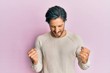 Kolları havada ve gözleri kapalı zaferi kutlayan, sıradan bir süveter giyen genç İspanyol. Kazanan konsept. 