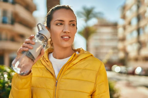 Gevşek yüzlü genç İspanyol kız şehirde bir şişe su içiyor..