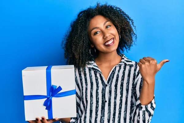 Hermosa Mujer Afroamericana Con Cabello Afro Sosteniendo Regalo Apuntando Pulgar — Foto de Stock