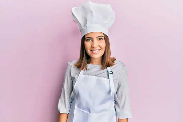 年轻美丽的女人穿着职业厨师的制服和帽子 脸上挂着快乐而冷静的微笑 幸运的人 — 图库照片