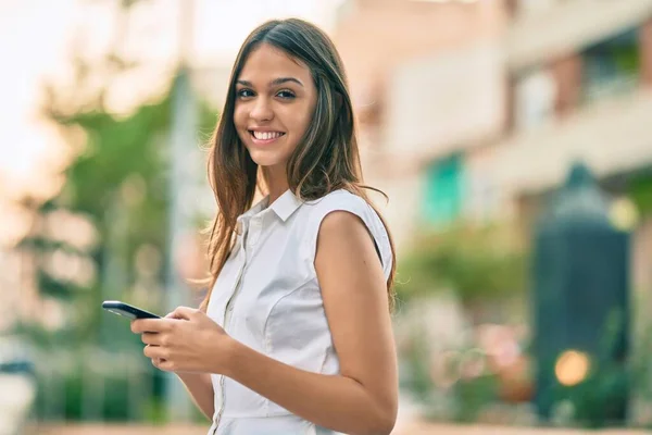 美しいですラテンティーン女の子笑顔幸せ使用してスマートフォンで市 — ストック写真