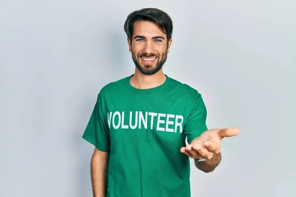 Giovane Uomo Ispanico Indossa Shirt Volontaria Sorridente Allegra Offerta Mano — Foto Stock