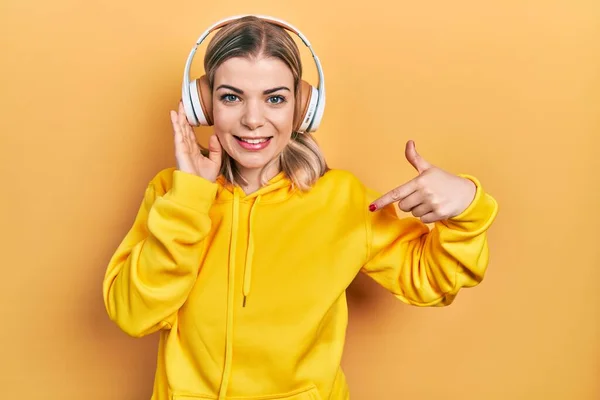 Hermosa Mujer Caucásica Escuchando Música Usando Auriculares Apuntando Con Dedo —  Fotos de Stock