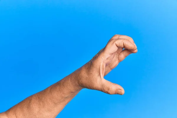 Hand Van Senior Spaanse Man Blauw Geïsoleerde Achtergrond Plukken Nemen — Stockfoto