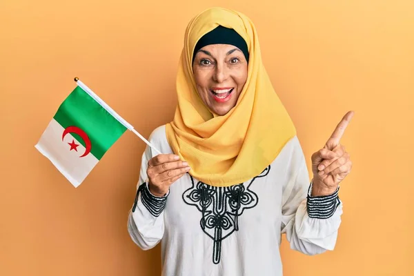 Mujer Hispana Mediana Edad Con Hiyab Sosteniendo Bandera Algeria Sonriendo —  Fotos de Stock