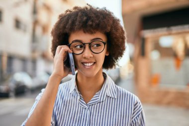 Genç İspanyol iş kadını gülümsüyor. Şehirdeki akıllı telefondan mutlu bir şekilde konuşuyor..