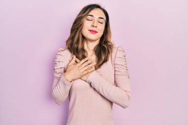 Elleri göğsünde gülümseyen, yüzünde minnet dolu bir jestle gülümseyen Latin asıllı genç bir kız. sağlık kavramı. 