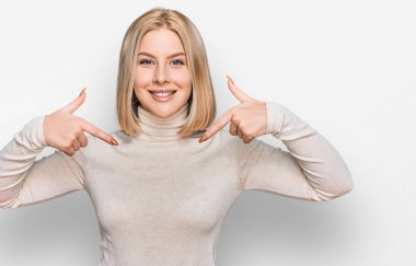 Gündelik kıyafetler giyen, kendine güvenen, gülümseyen, kendini gururlu ve mutlu gösteren genç sarışın kadın.. 