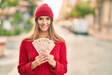 Şehirde elinde Türk lirası banknotları tutan yün şapkalı genç İspanyol kadın..