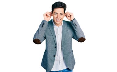 İş kıyafetleri giymiş, gülümseyen, parmaklarıyla kulaklarını çeken genç İspanyol bir adam, komik bir jest. deneme sorunu 