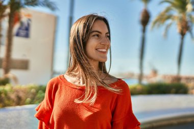 Genç İspanyol kadın gülümseyerek şehirde mutlu mesut dikiliyor..