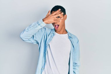 Genç, Afro-Amerikalı bir adam. Günlük kıyafetler giymiş. Şoka girmiş, yüzünü ve gözlerini kapamış, utanmış bir ifadeyle parmaklarından bakıyor.. 