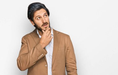 İş kıyafetleri giyen genç İspanyol bir adam bir soru hakkında endişeli ve gergin bir şekilde düşünüyor. 