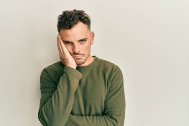 Günlük kıyafetler giyen genç İspanyol adam kollarını kavuşturarak depresyondan sıkılmış ve yorgun görünüyor.. 