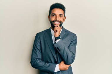 Sakallı, takım elbiseli ve kravatlı yakışıklı kolları çapraz ve çenesi açık kameraya gülümseyen yakışıklı bir adam. Olumlu düşünmek. 