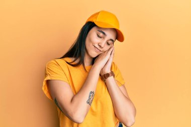 Genç İspanyol kadın teslimat üniforması giyiyor ve şapka takıyor. Yorgun uyuyor. Hayal kuruyor, ellerle poz veriyor ve gözleri kapalı gülümsüyor.. 