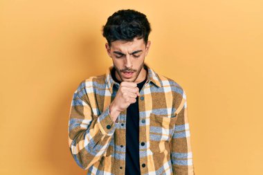 Günlük kıyafetler giyen genç İspanyol adam kendini iyi hissetmiyor ve soğuk algınlığı veya bronşitin belirtisi olarak öksürüyor. sağlık hizmeti kavramı. 