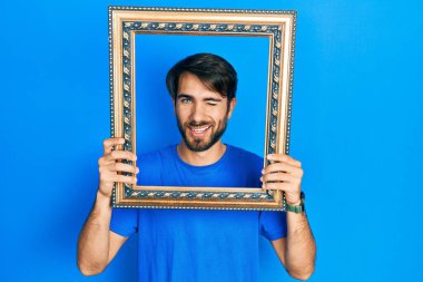 Genç İspanyol adam elinde boş bir çerçeve ile kameraya bakıyor. Seksi bir ifadeyle, neşeli ve mutlu bir yüzle.. 