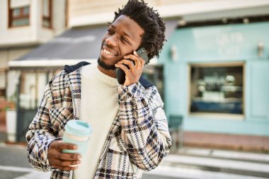 Afro saçlı yakışıklı siyahi adam telefonda konuşuyor.
