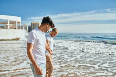 Genç eşcinsel çift mutlu bir şekilde sahilde yürüyor..