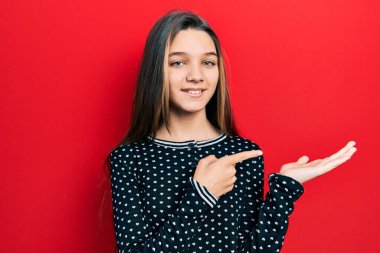 Genç esmer kız, gündelik süveter giyip kameraya hayret ediyor ve gülümsüyor.. 