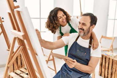 Sanat okulunda resim yaparken gülümseyen orta yaşlı öğrenci ve öğretmen..