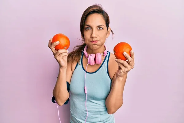 Junge Lateinamerikanische Frau Turnbekleidung Mit Kopfhörern Und Orangen Der Hand — Stockfoto
