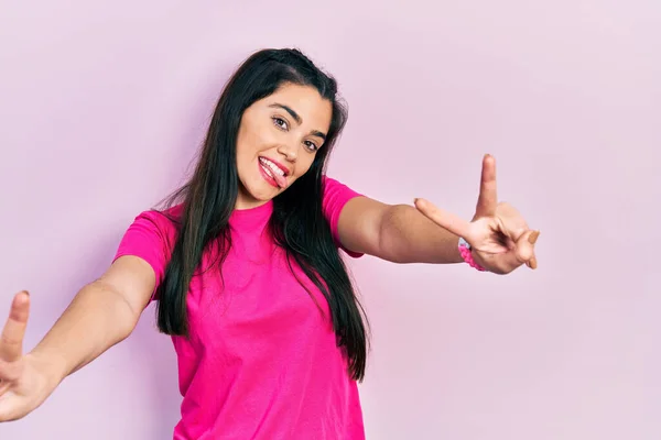분홍색 티셔츠를 웃으며 승리의 표시를 스페인 소녀가 — 스톡 사진