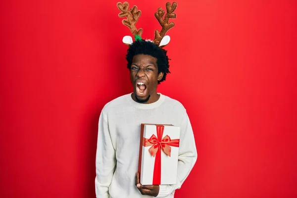 Jovem Afro Americano Vestindo Chapéu Natal Veado Segurando Presente Irritado — Fotografia de Stock