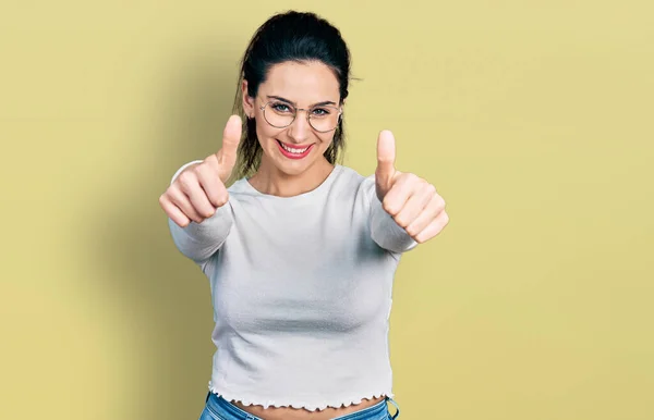 手で積極的なジェスチャーを行うことを承認カジュアル服を着て若いヒスパニック女性 親指アップ笑顔と成功のために幸せ 勝者のジェスチャー — ストック写真