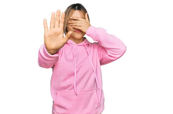 年轻的高加索女人穿着宽松的运动衫 用手捂住眼睛 用悲伤和恐惧的表情做停止动作 尴尬和消极的概念 — 图库照片