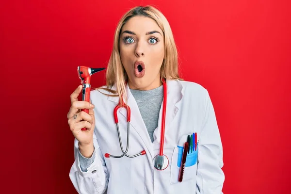 Mujer Joven Caucásica Vistiendo Uniforme Médico Sosteniendo Otoscopio Asustado Sorprendido —  Fotos de Stock