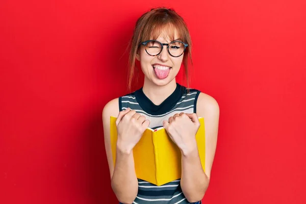 Rödhårig Ung Kvinna Läser Bok Bär Glasögon Sticker Tungan Glad — Stockfoto