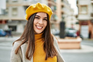 Genç İspanyol kız gülümseyerek şehirde mutlu mesut dikiliyor..