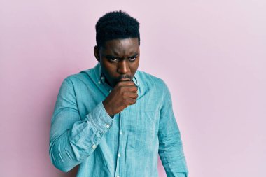 Yakışıklı, sıradan kıyafetler giyen, kendini kötü hisseden ve soğuk algınlığı veya bronşitin belirtisi olarak öksüren siyahi bir adam. sağlık hizmeti kavramı. 