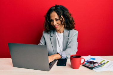Ofiste çalışan orta yaşlı güzel bir kadın mutlu ve havalı bir gülümsemeyle bir fincan kahve içiyor. şanslı kişi. 
