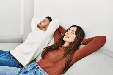 Genç İspanyol çift evde kanepede elleri üzerinde dinleniyor..