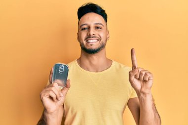 Elinde konserve yiyeceklerle gülümseyen genç bir Arap adam bir fikir veya soruyla mutlu bir yüzle işaret ediyor. 