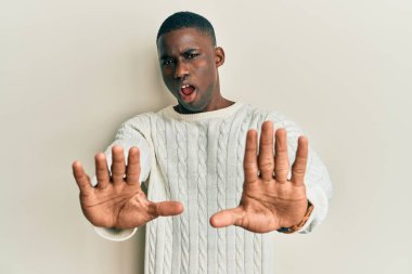 Gündelik kıyafetler giyen genç Afro-Amerikan adam avuç içi hareketlerini durduruyor, kızgın ve hayal kırıklığı ifadesi takınıyor. 