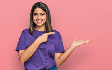 Gündelik mor tişört giyen genç İspanyol kız kameraya hayret ediyor ve gülümsüyor.. 