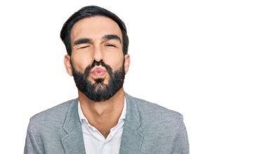 Genç İspanyol bir adam iş kıyafetleri giymiş kameraya bakıyor ve güzel ve seksi bir şekilde havadan öpücük yolluyor. aşk ifadesi. 