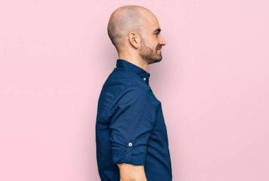 Latin kökenli genç bir adam günlük giysiler giyiyor, rahat bir görünüm takınıyor, doğal bir yüz ifadesi ve kendinden emin bir gülümsemeyle poz veriyor.. 