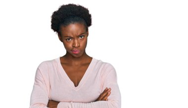 Genç Afro-Amerikan kızı gündelik kıyafetler giyiyor şüpheci ve gergin, yüzünde çapraz kollarla onaylamayan bir ifade var. negatif kişi. 